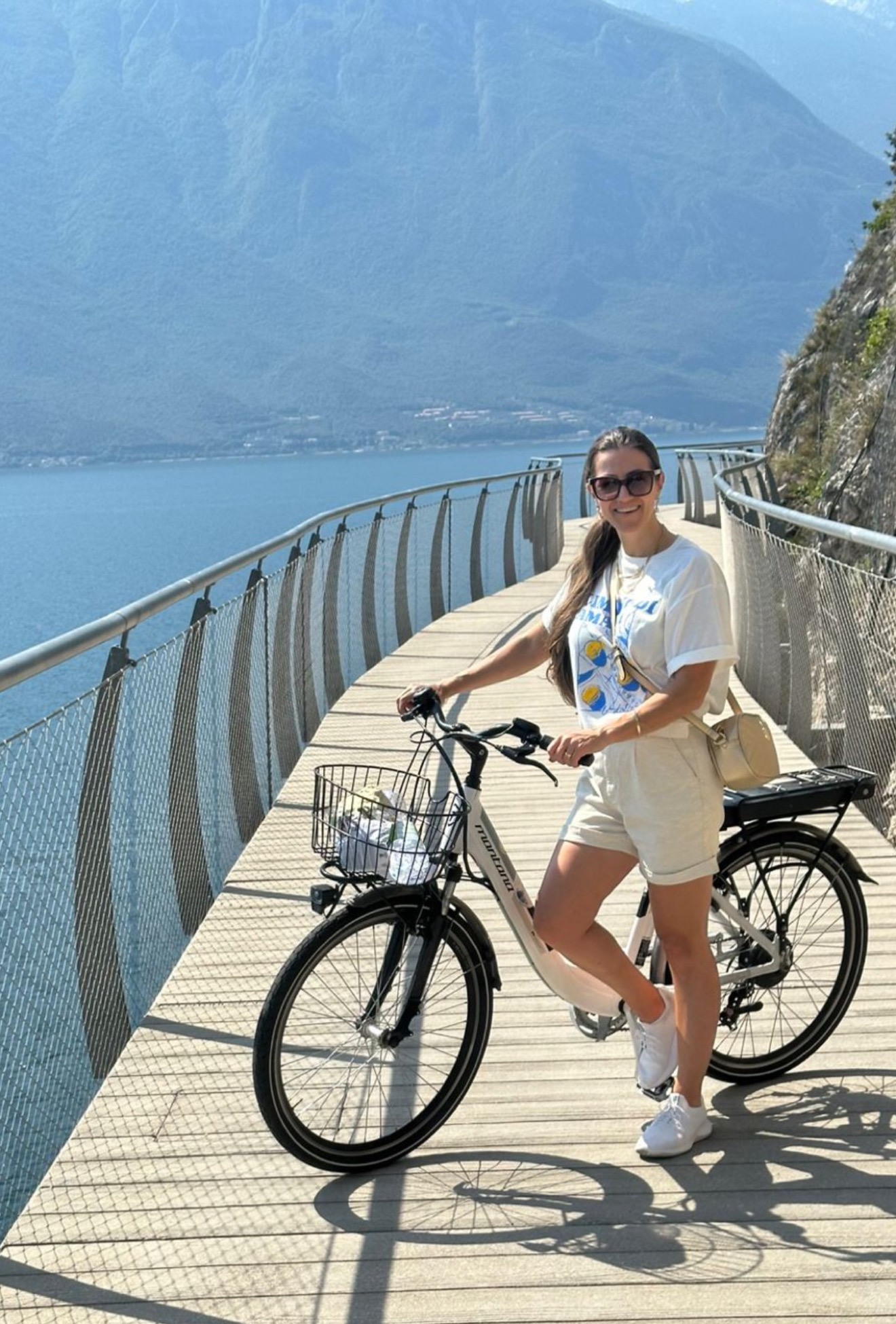 Woman with an electric city bike on the suspended Ciclovia di Limone